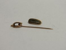 9ct gold stick pin with horseshoe shape top with red stone & a gold coloured mourning brooch.