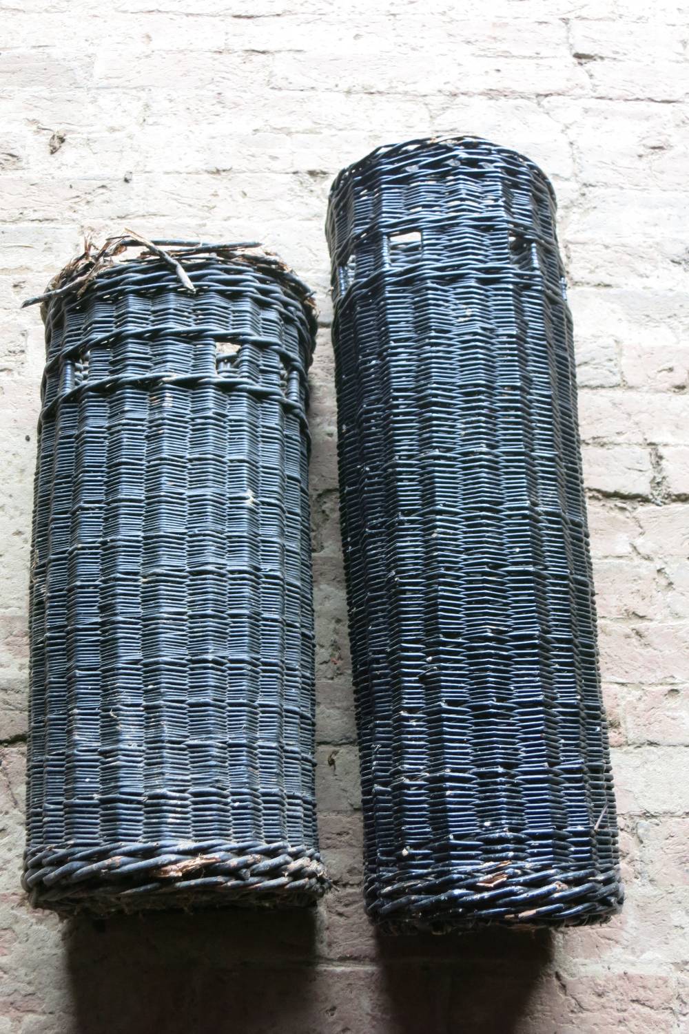 Two black painted wicker umbrella baskets and a wicker coach horn case