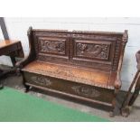 Carved oak settle with rising seat to storage, 137cms x 45cms x 97cms. Estimate £200-250.