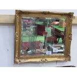 Gilt framed ornately decorated bevel edge wall mirror. Estimate £20-40.