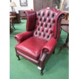 Leather wing back button back armchair. Estimate £50-70.