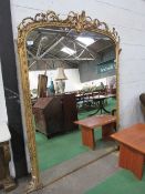 Very large arched top gilt framed wall mirror with decorated foliage to top, 220cms x 164cms.