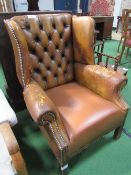 Leather button back wing backed arm chair. Estimate £40-50.