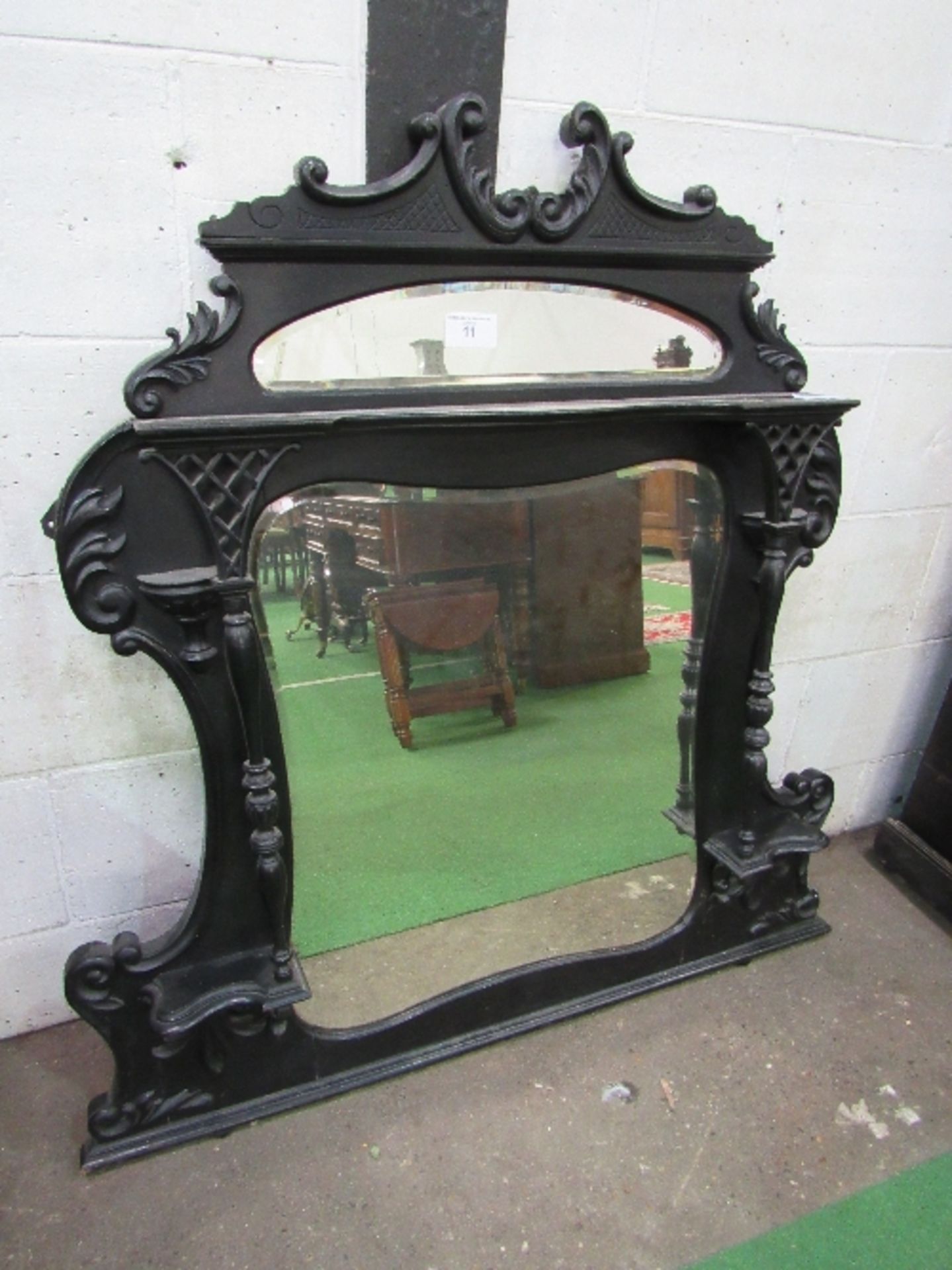 Ebonised ornate over mantle mirror with shaped sides, 130cms x 124cms. Estimate £30-50.