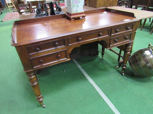 Mahogany writing desk on turned legs to casters, 122cms x 57cms x 77cms. Estimate £80-100.