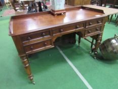 Mahogany writing desk on turned legs to casters, 122cms x 57cms x 77cms. Estimate £80-100.