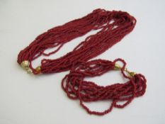 Red coloured coral like necklace & bracelet. Estimate £40-60.