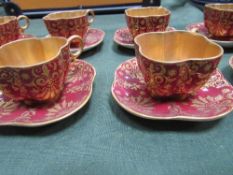 Set of 8 Coalport shamrock-shaped red & gold coffee cups & saucers. Estimate £30-40.