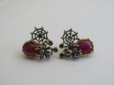 Hannah May ruby & sapphire silver earrings, decorated with a spider & web. Estimate £150-200.