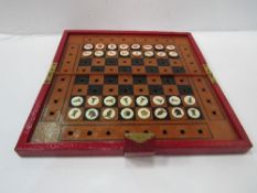 Red leather bound case containing chess board & travelling chess set.