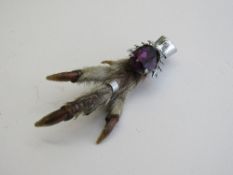 Amethyst coloured gemstone on bird's claw brooch. Estimate £40-60.