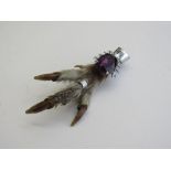 Amethyst coloured gemstone on bird's claw brooch. Estimate £40-60.