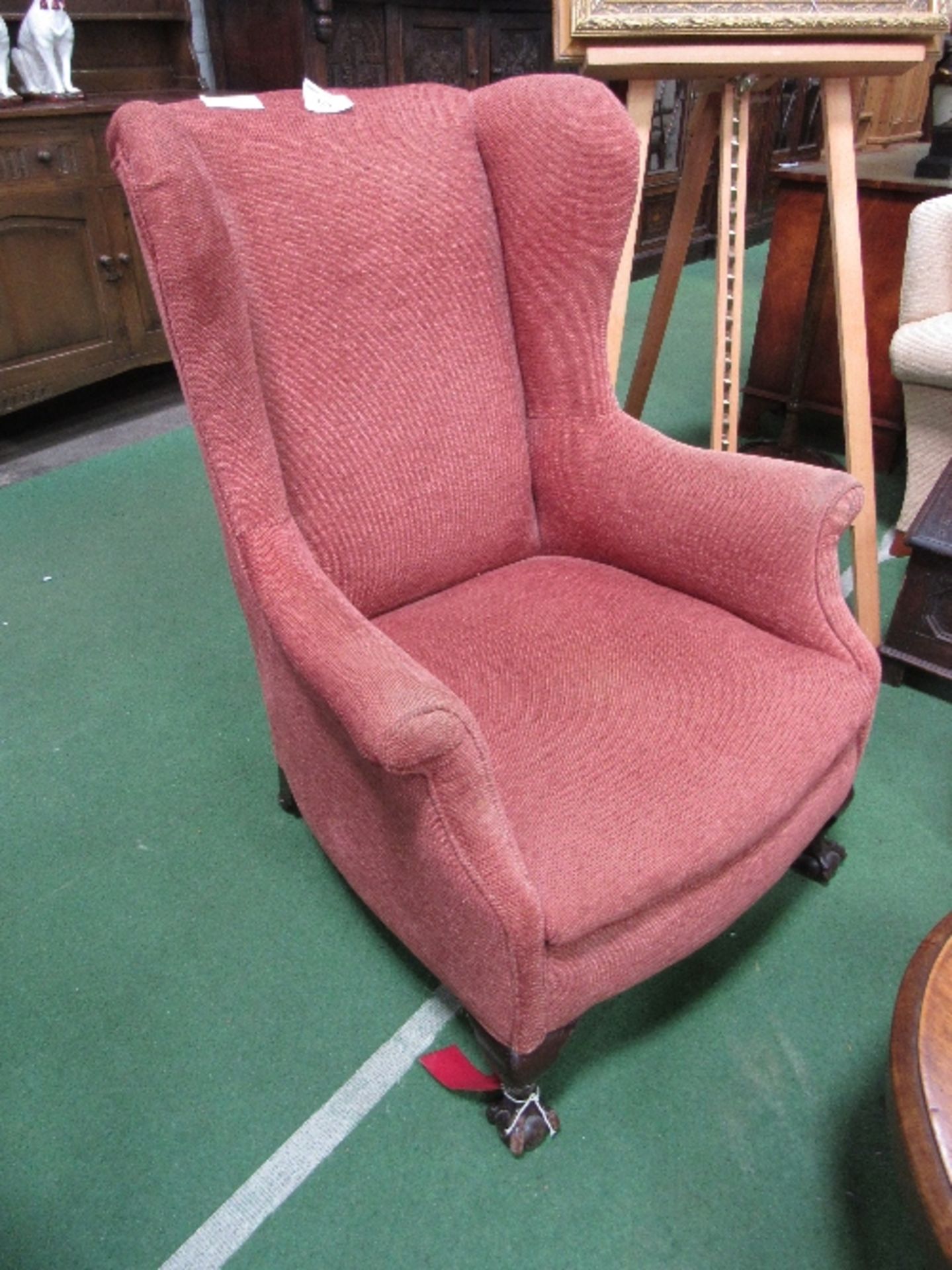 Red upholstered wing back chair on ball & claw feet to front. Estimate £30-50