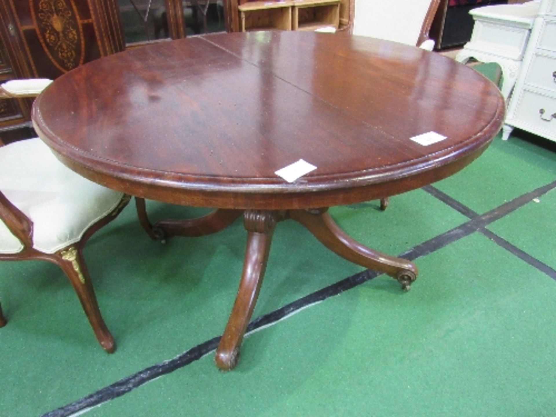 Mahogany circular tilt-top table on heavy turned column to 3 scrolled feet with casters, diameter