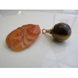 Carved possibly red jade pendant & a gold metal mounted tiger's eye pendant. Estimate £20-40