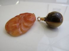 Carved possibly red jade pendant & a gold metal mounted tiger's eye pendant. Estimate £20-40