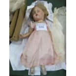 Bisque doll with opening & closing eyes, blonde hair, pink silk dress & a boxed artificial flower