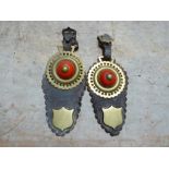 Pair of shaped leather headpieces each with a horse brass with red ceramic boss, shield stud and