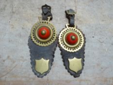 Pair of shaped leather headpieces each with a horse brass with red ceramic boss, shield stud and