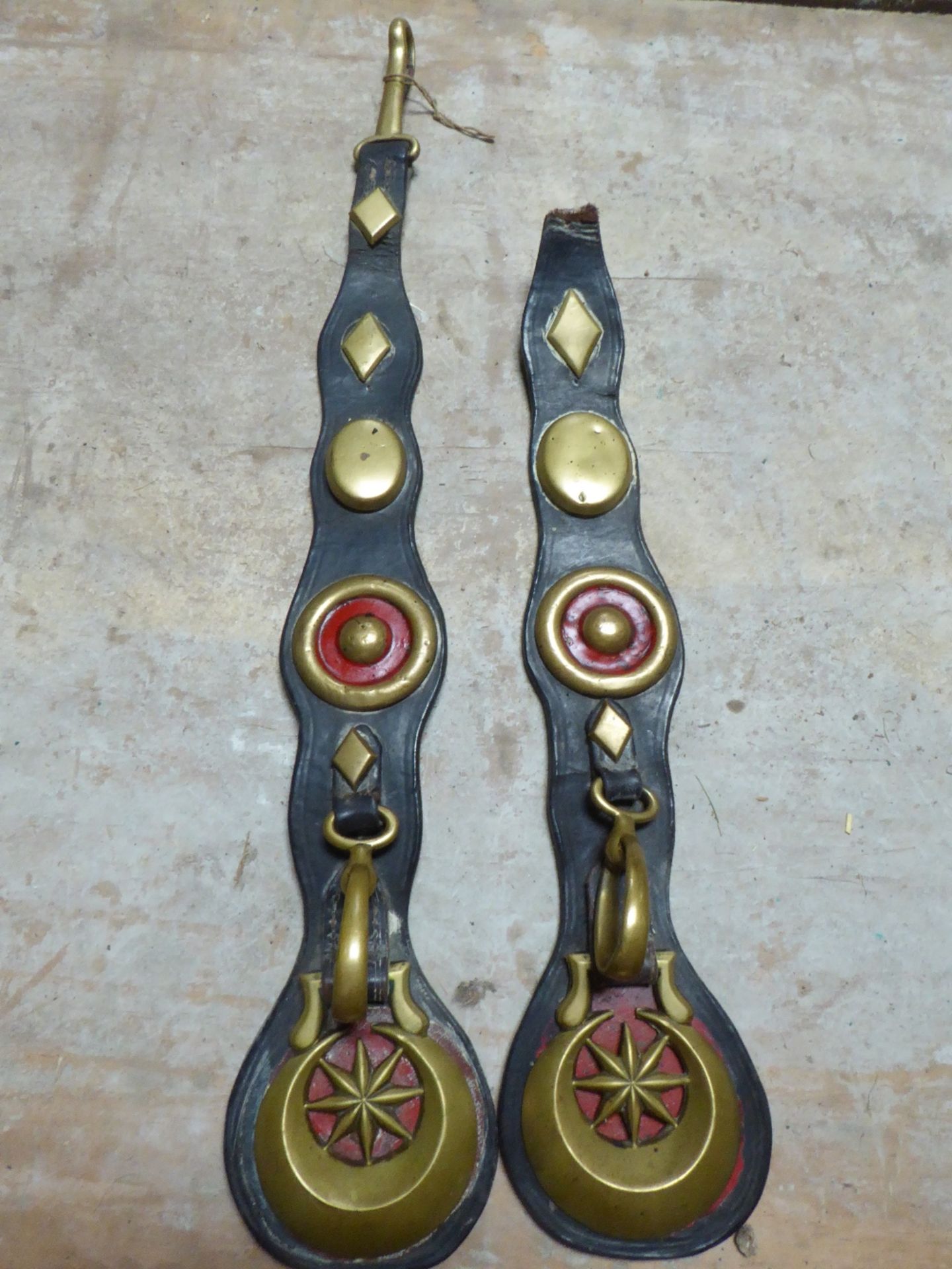 Pair of long leather straps each with a crescent horse brass, brass rein carrier, diamond and oval
