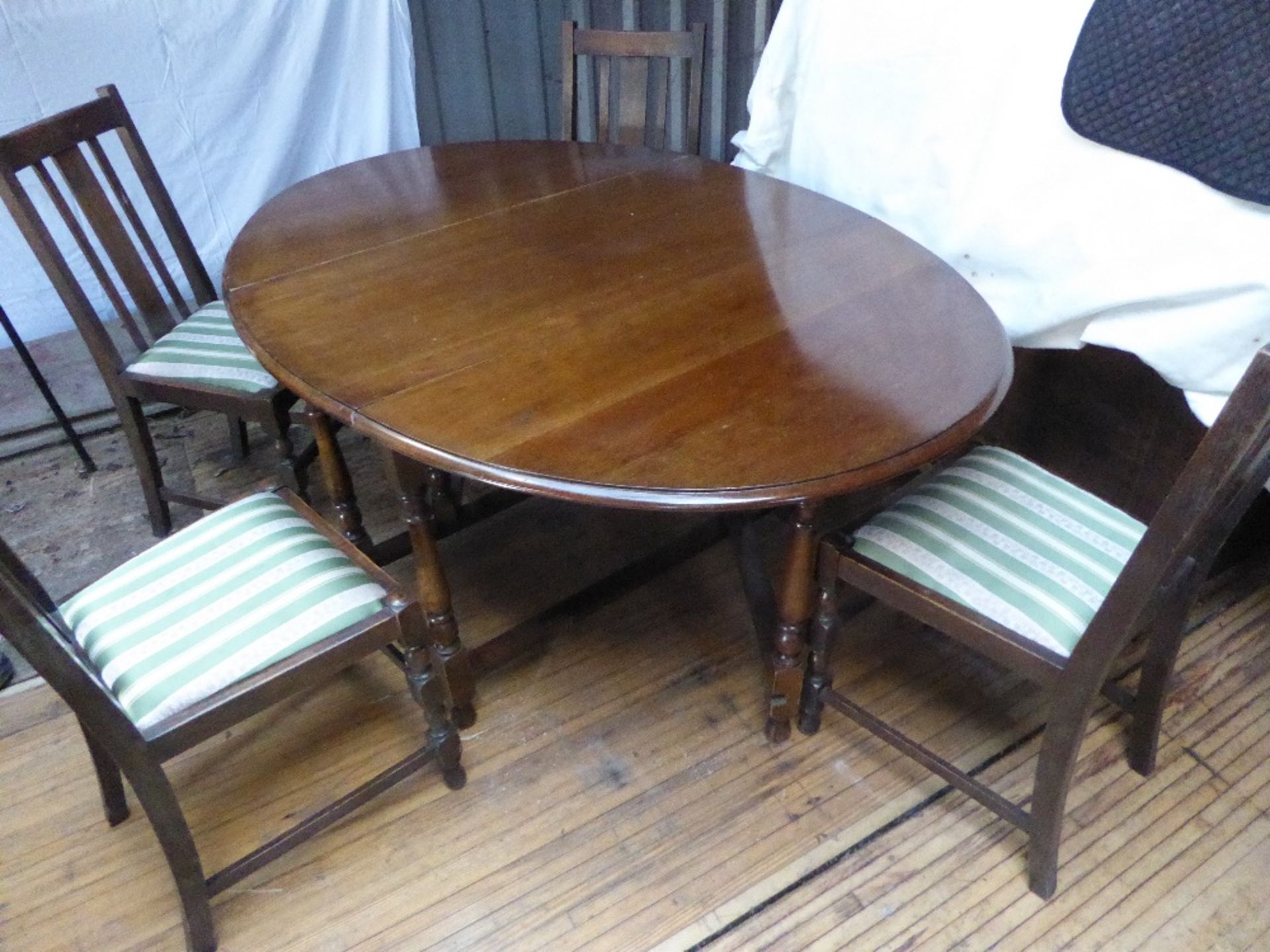 Brown mahogany gate leg table with four chairs upholstered in green striped material