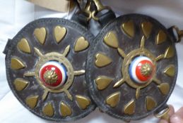 Pair of circular leathers each edged with 12 brass hearts and a central brass ship's wheel with a