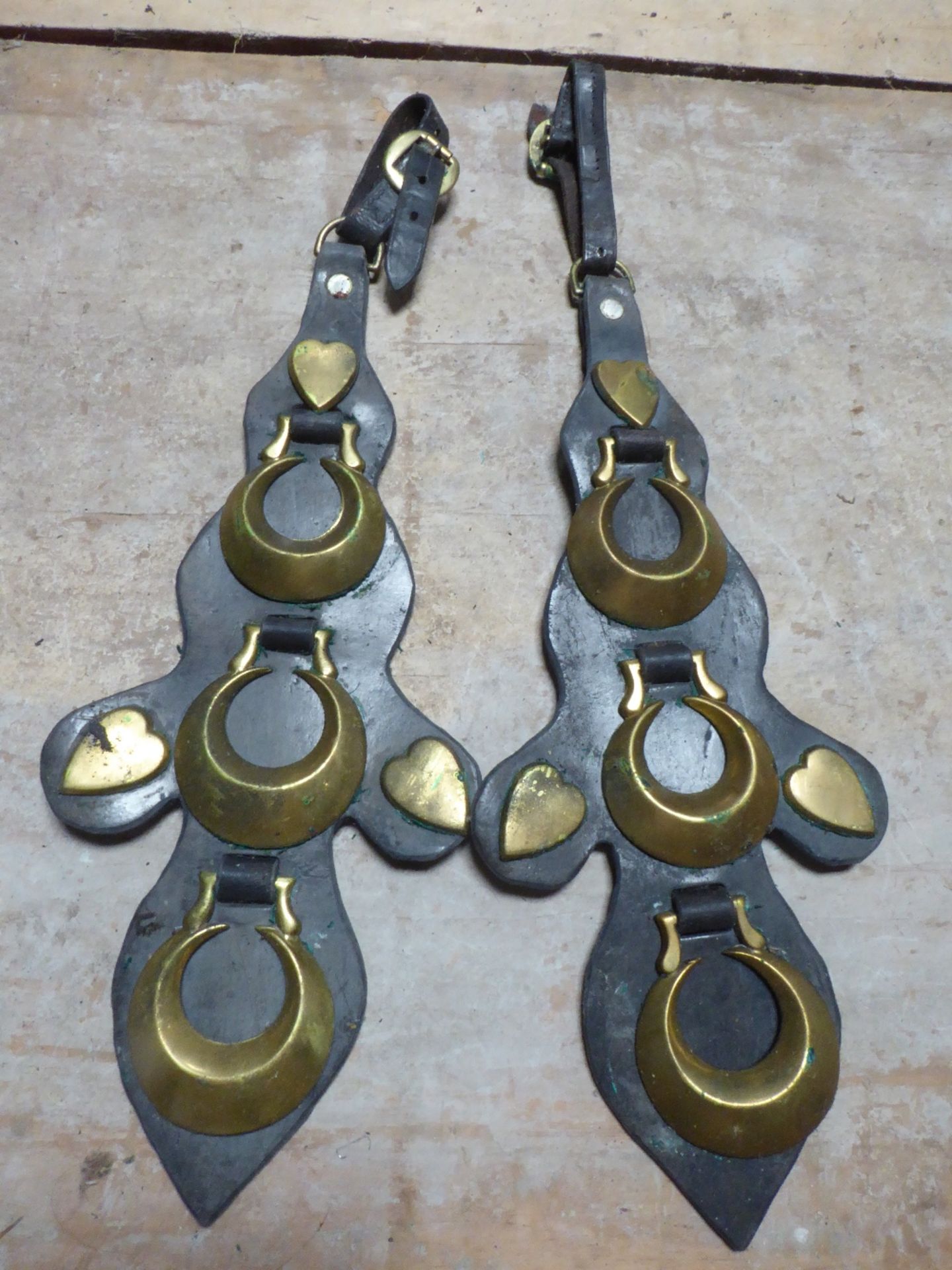 Pair of unusual shaped leathers each with three crescent horse brasses, three heart studs and