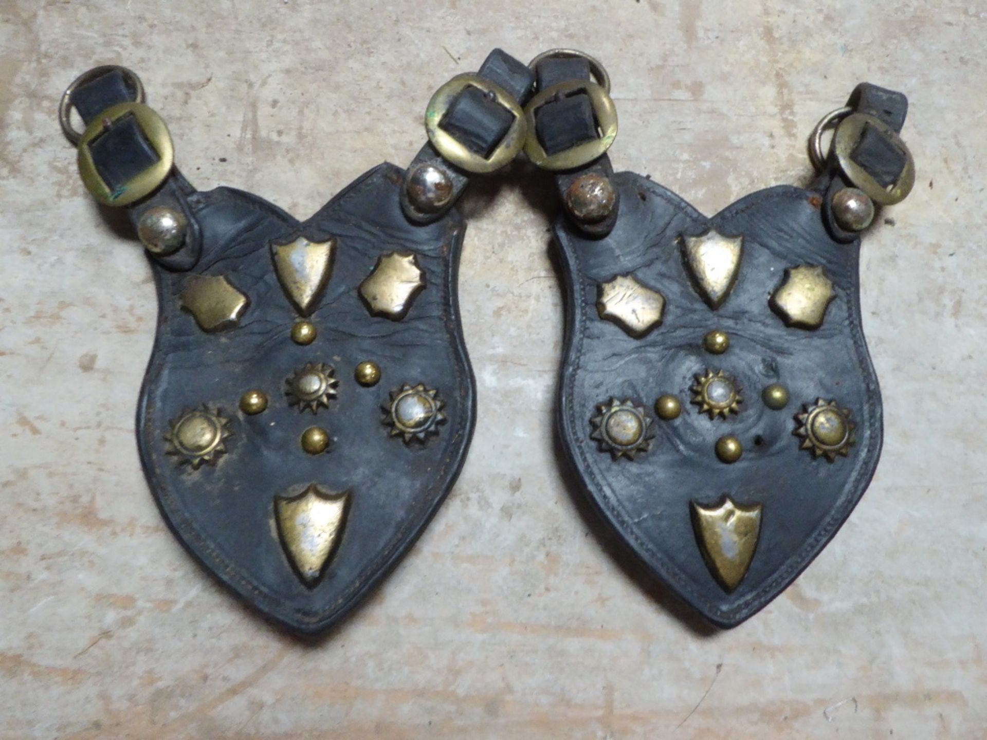 Pair of shaped leathers each with various brass studs and buckle
