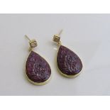 Large tear drop shaped natural carved ruby with Princess cut diamond earrings set in yellow metal.