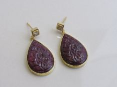 Large tear drop shaped natural carved ruby with Princess cut diamond earrings set in yellow metal.