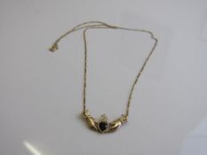 9ct gold pendant with a black heart-shaped stone in 2 hands on 9ct gold chain, weight 2.5gms.