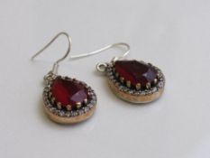 Tear dropped shaped red stone & silver coloured metal earrings. Estimate £30-40
