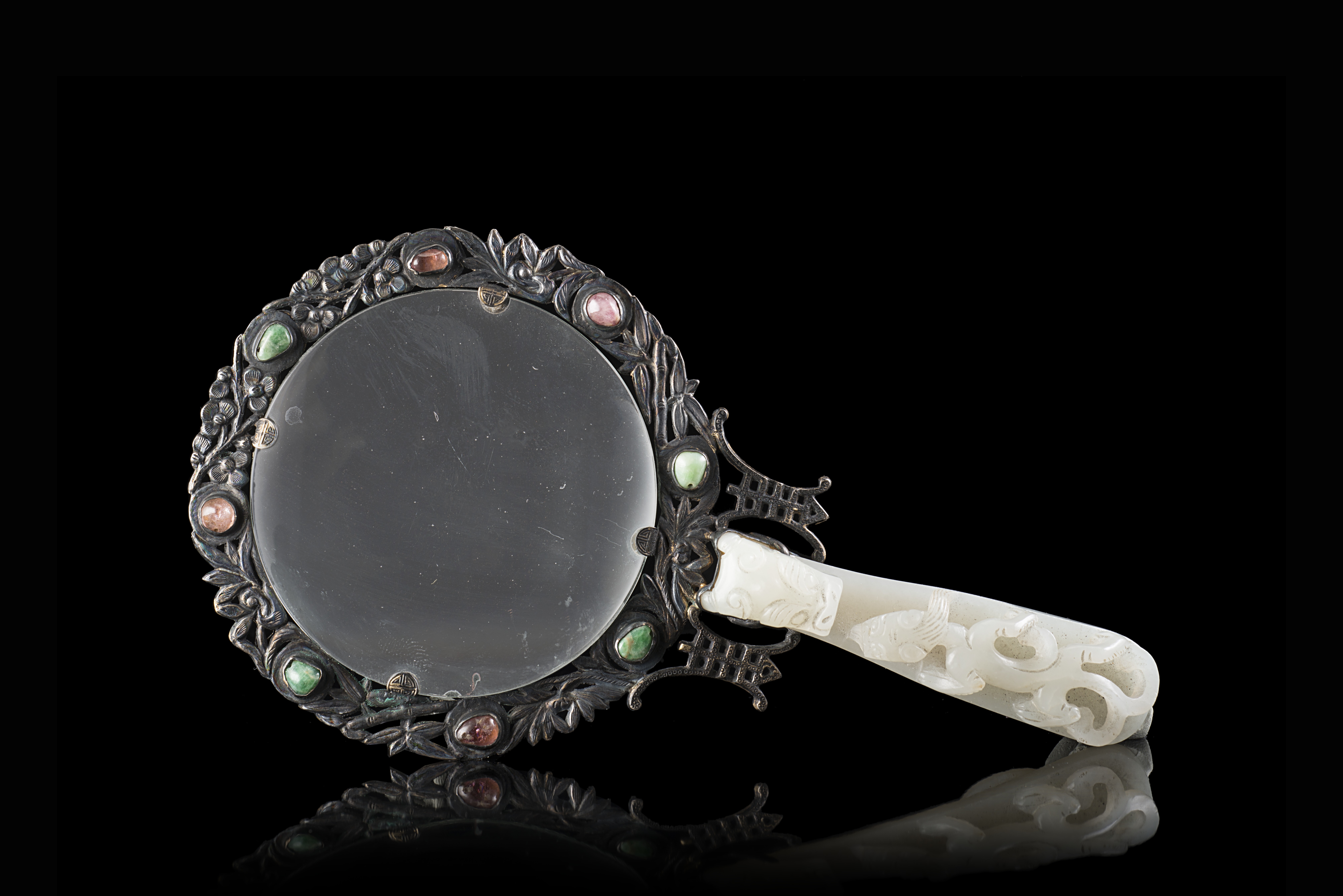 A magnifying glass with a pale celadon handle carved as a dragon, mounted with silver and inset