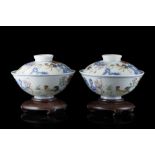 A pair of doucai cups and covers decorated with a boy tending to cockerels and calligraphy, with