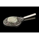 A silver mirror with an ivory handle, decorated with a celadon plaque incised with figures in a