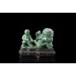 A green jadeite sculpture of children at play with a Buddhist lion, with wood baseChina, 19th