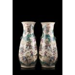 A pair of twin handled polychrome vases, each decorated with figures in battle and procession on a