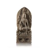 A grey stone stele carved with a seated Guanyin wearing long robes, the mandorla with more