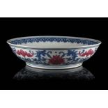 A blue and white and copper red porcelain saucer decorated with stylised lotus flowers, bats and