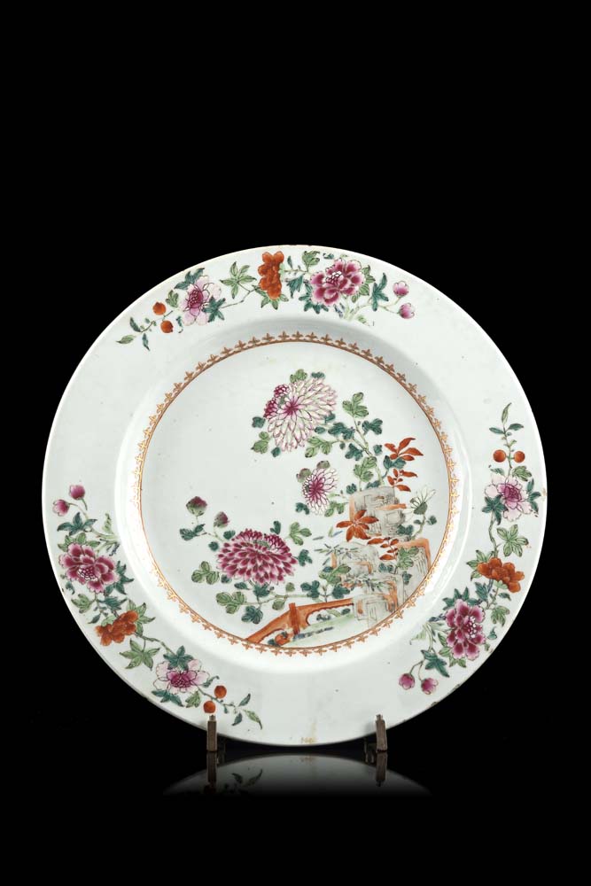 A Famille Rose dish decorated with a central scenes of flowering peonies in a spear-head border (