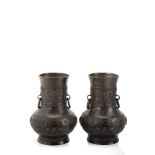A pair of bronze vases with twin ring handles, decorated in relief with parallel bands of archaistic