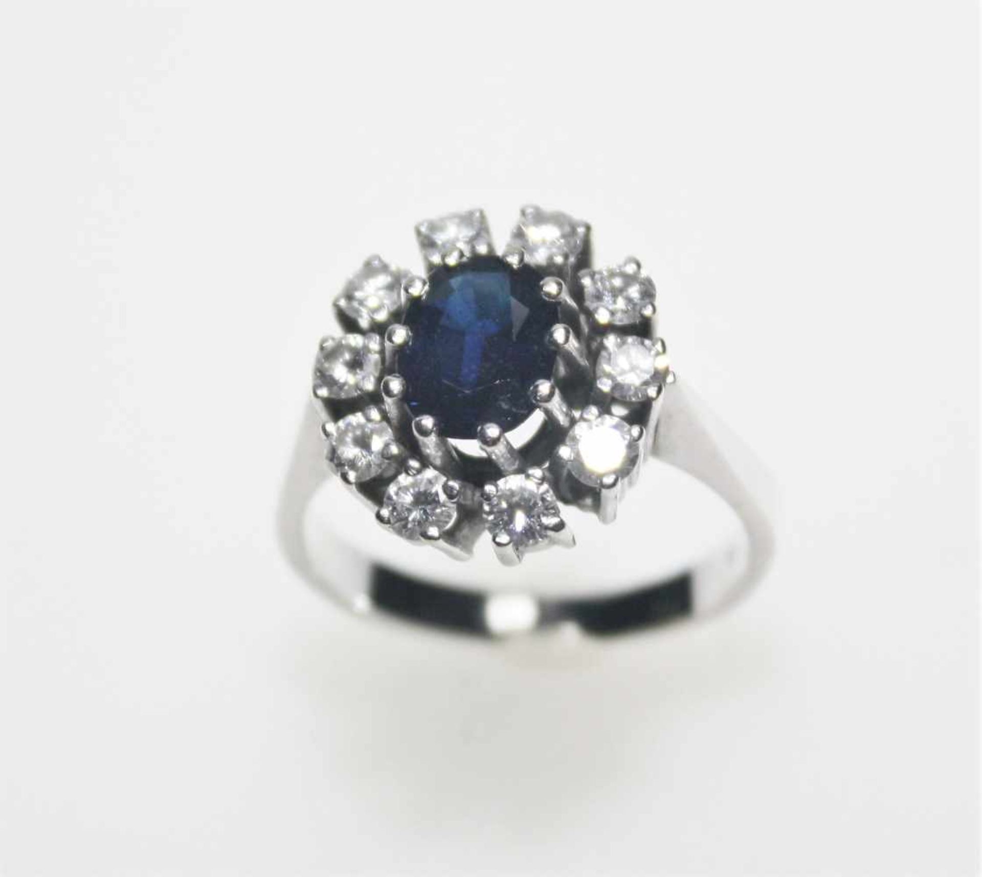 Weißgoldring 585/f gest. mit einem oval facettierten, dunkelblauen Saphir umgeben von Diamanten in