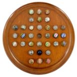 A large Victorian mahogany solitaire board with 32 German pontilled glass marbles including swirls,