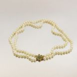 A double string pearl necklace, with 9 carat gold clasp set with emeralds and diamonds