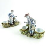 Pair of Dutch Delft figural cruets, circa 1800, modelled as a male and female sat on a tree stumps