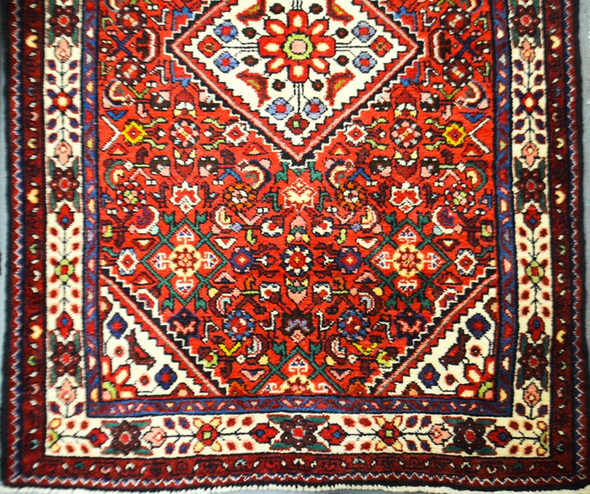 A Caucasian lilian design deep crimson rug, 107cm x 152cm