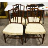 A set of four upholstered dining chairs with central column splats
