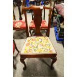 A uptright chair with floral embroidered seat