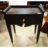A black lacquered side cabinet, with tapered supports and single long drawer with brass handle