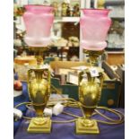 A pair of lacquered brass oil lamps with rose glas